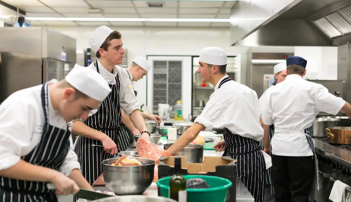 Catering students cooking in a kitchen.