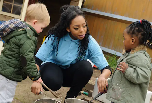 Childcare student working with two nursery age children.