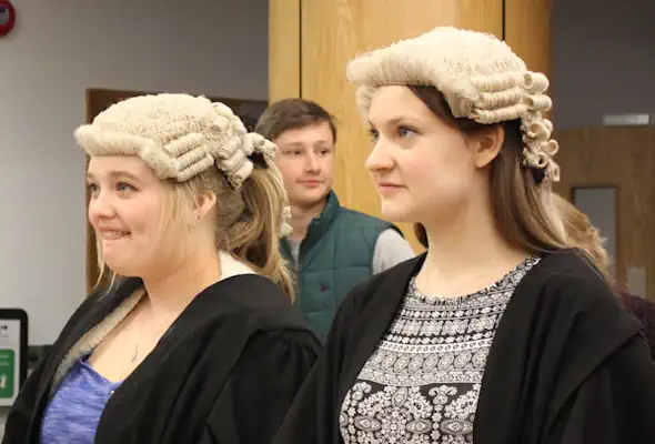 Two students in white wigs taking part in a mock trial.