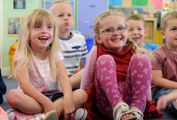nursery age children sitting on the floor smiling