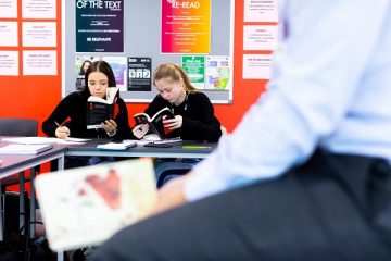 two female students reading books in class