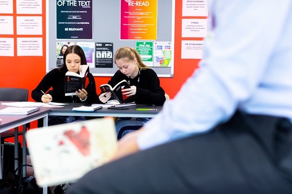two female students reading books in class