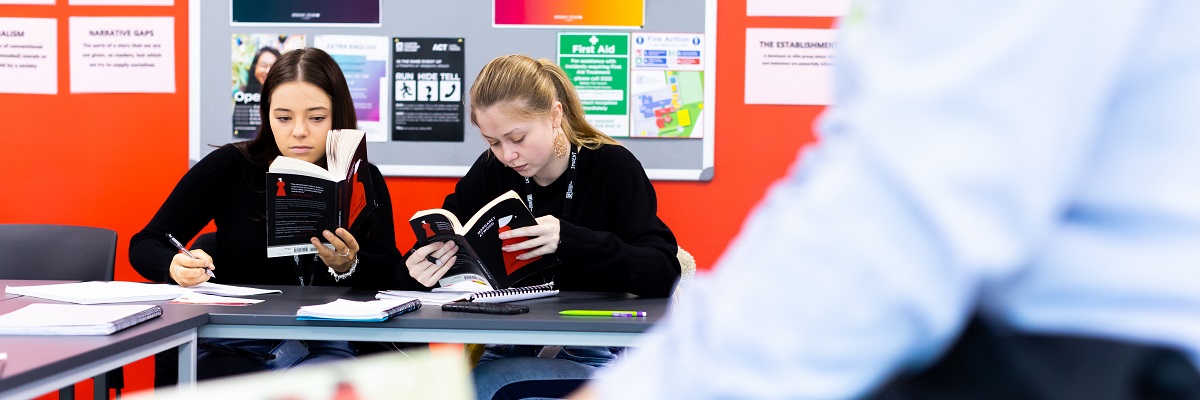 two female students reading books in class