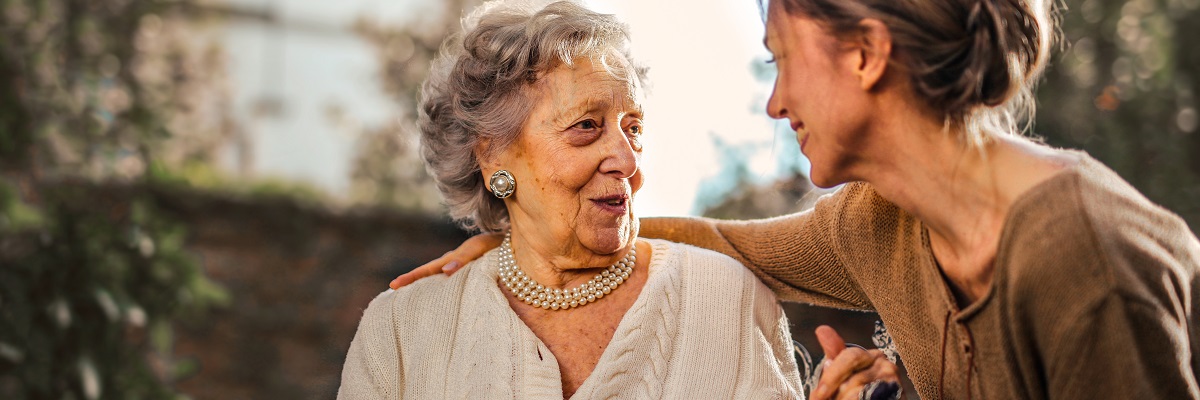 a women embracing and holding hands with an elderly woman in a wheelchair