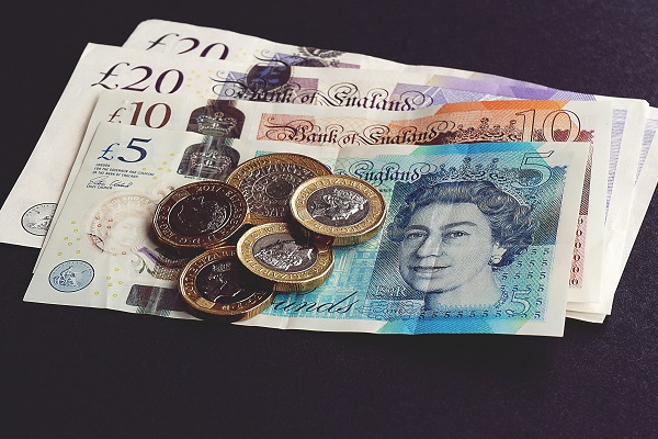 Twenty, Ten and five pound notes in pile with two and one pound coins on top