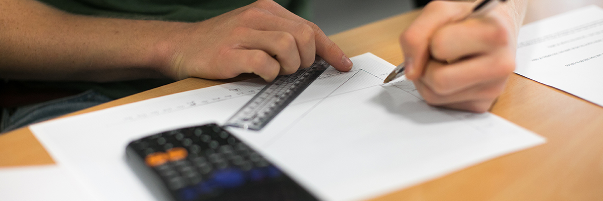 someone with a ruler, pencil, paper and calculator