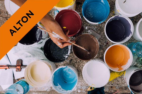 pots of different coloured paint on the floor with someone dipping their paintbrush in one