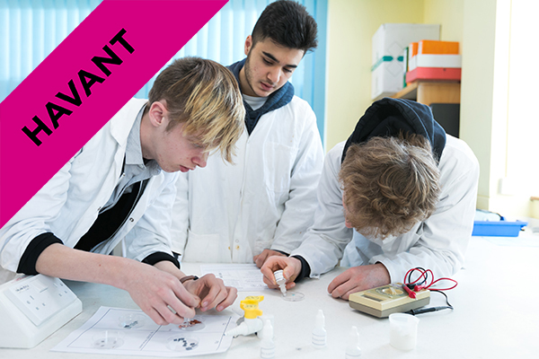 three students in lab coats in class