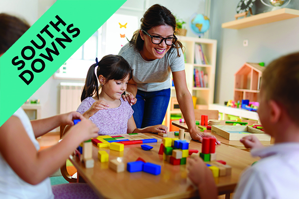 Preschool teacher with children playing with colourful wooden didactic toys at nursery