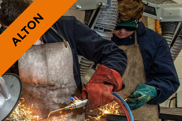 two students in engineering workshop working at benches with protective eyewear