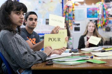 students holding up french words in class