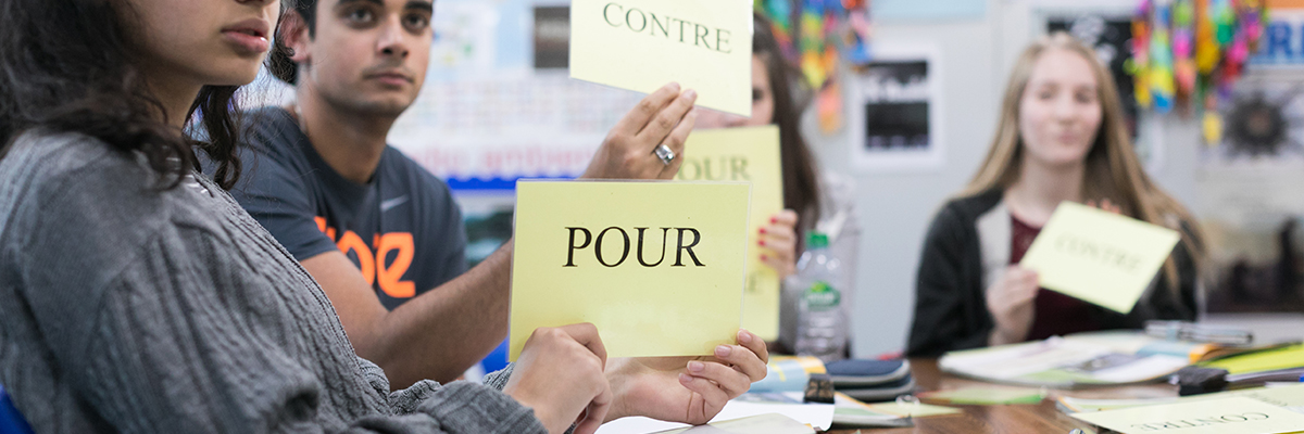students holding up paper with french words on