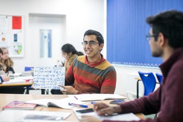 a student holding up math equations in class