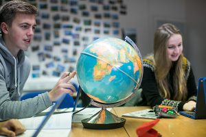 a student pointing at a globe