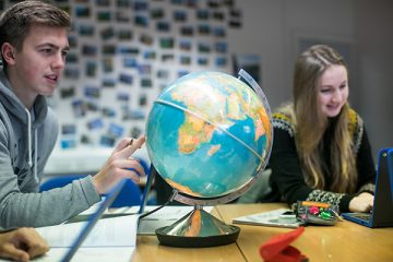 a student pointing at a globe
