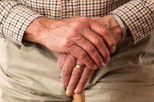 closeup of an elderly person's hands holding a walking stick