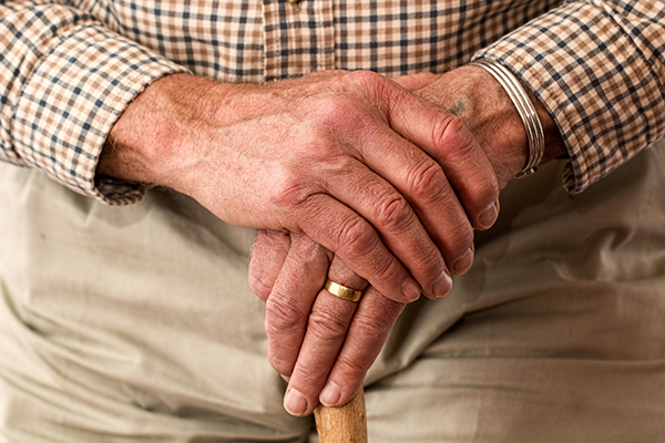 an elderly persons hands holding a walking stick
