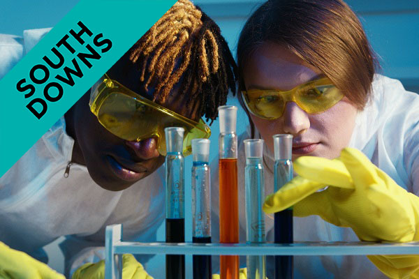 two students with goggles on looking at chemicals in test tubes