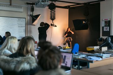 student taking a photo of someone in a photography studio