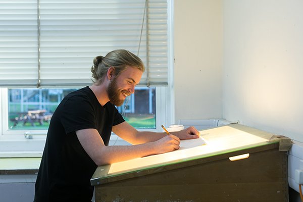 a male student working at a drawing desk
