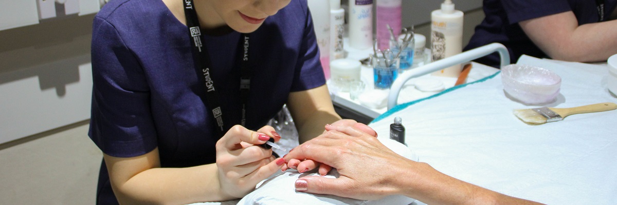 a beauty student giving a client a manicure