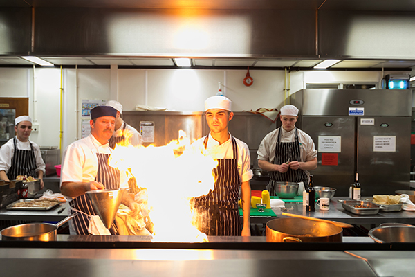 students cooking with fire in college kitchen
