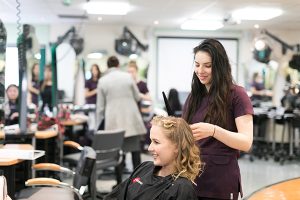 a student doing a fellow student's hair