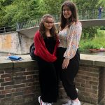 two students in front of bridge over river