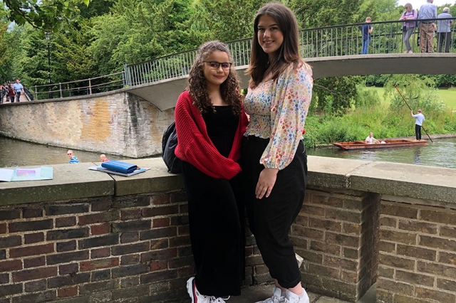 two students in front of bridge over river