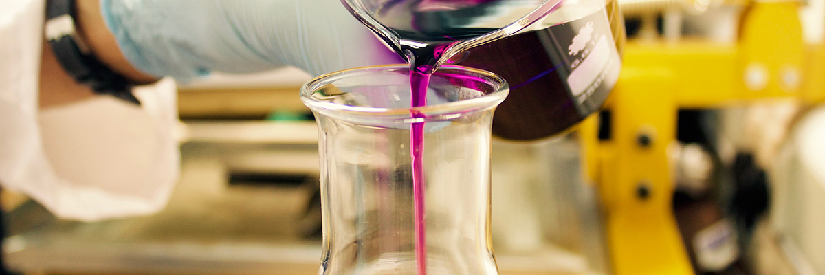 chemicals being poured into a beaker