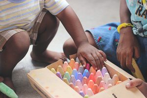 young child playing with large box of crayons