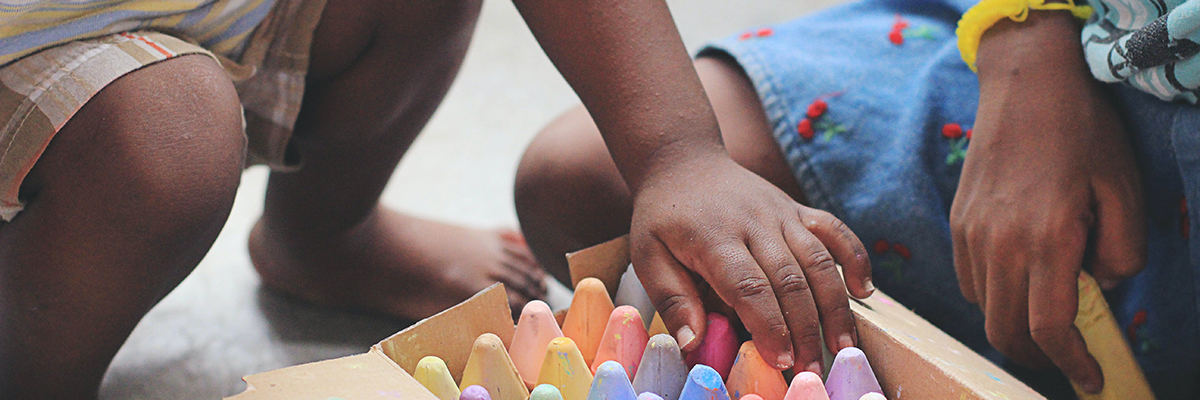 child playing with pastel crayons