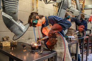 student working at a bench in engineering workshop wearing protective eyewear
