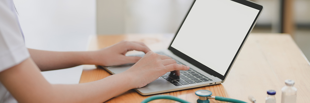 close up of someone typing on laptop with a stethoscope
