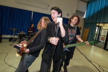 three male students performing in a band