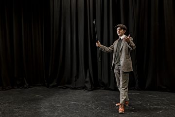 a student performing in a play on stage in costume