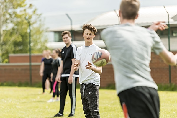 Alton male students playing passing a rugby ball to each other