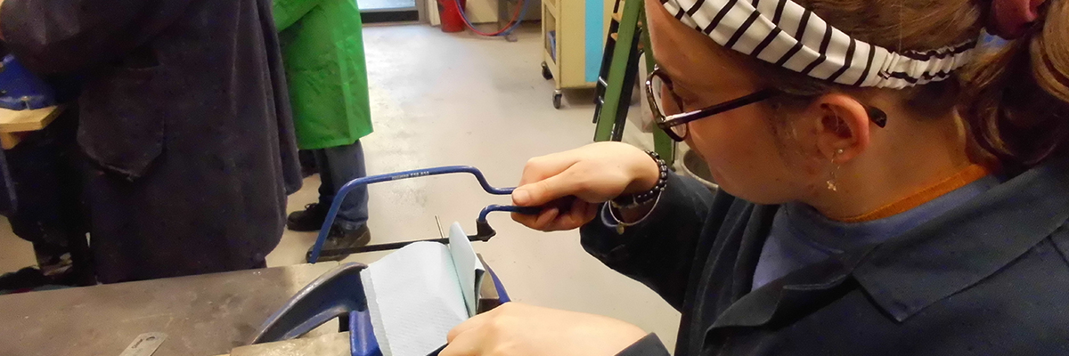 student in workshop using a hand saw