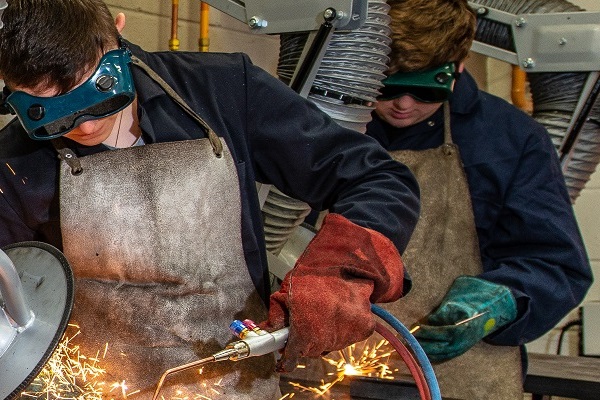two students in engineering workshop working at benches with protective eyewear