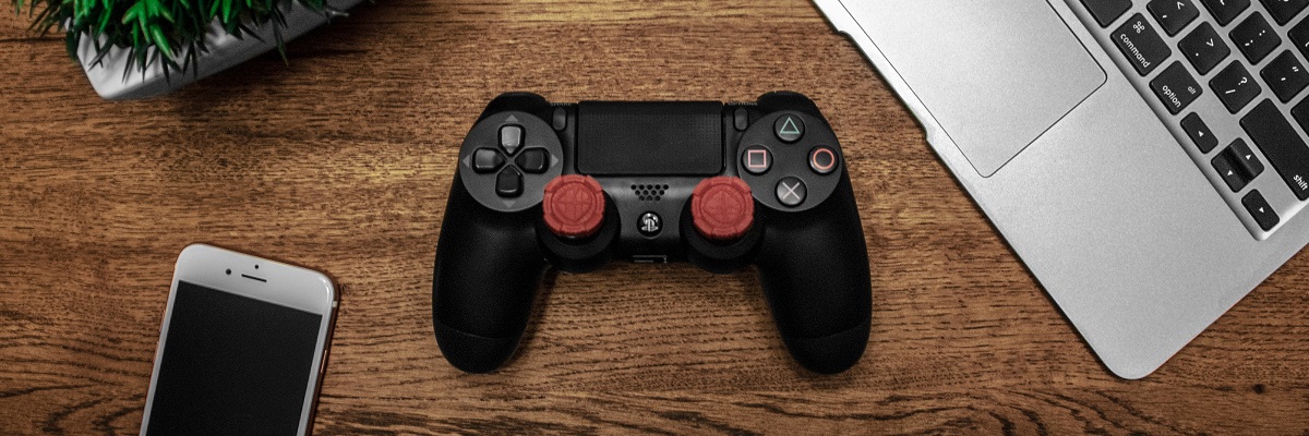 a ps4 controller, headphones, laptop and iphone on a desk
