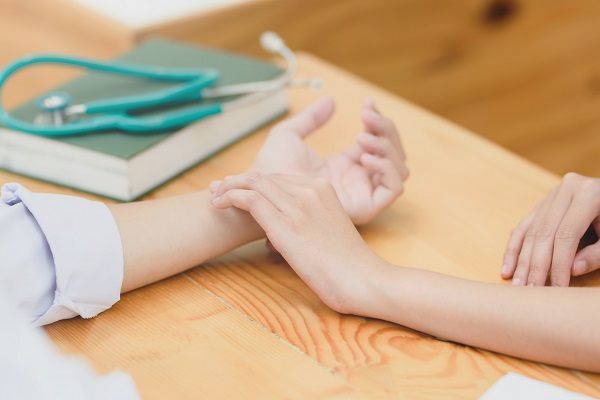 a nurse taking someone's pulse on their wrist