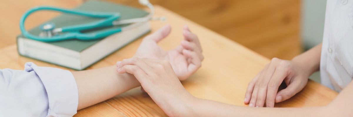 a nurse taking someone's pulse on their wrist