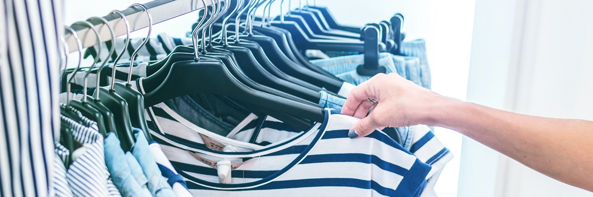 someone browsing through clothing on a rail in a store