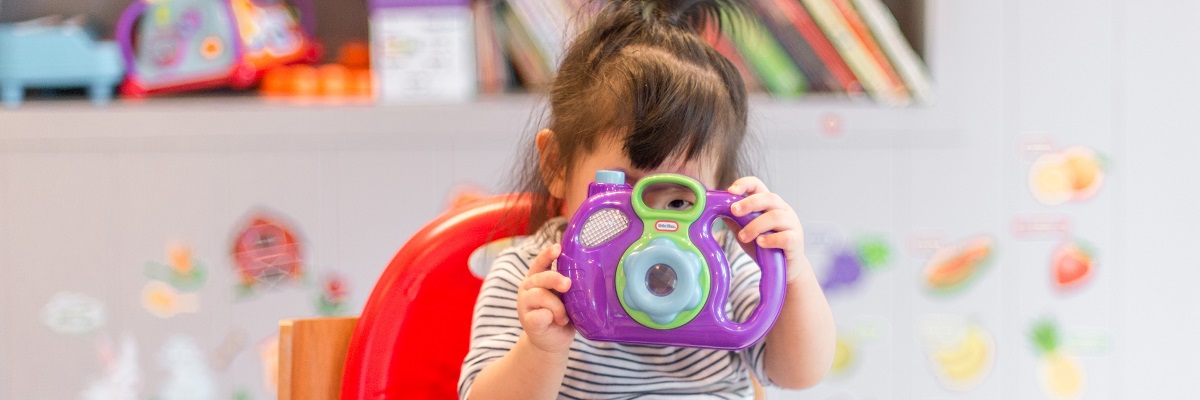 young child playing with a toy camera