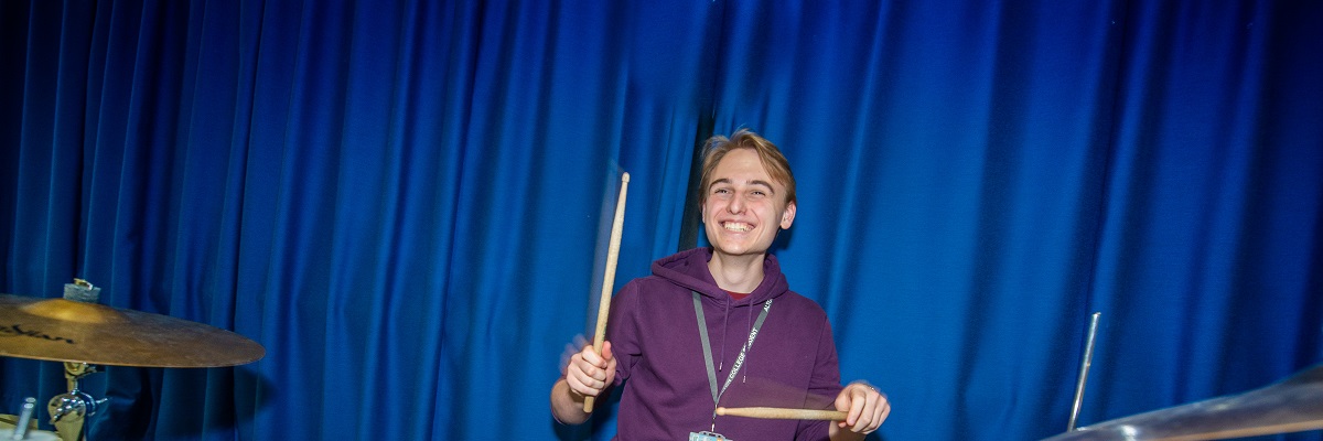 male student playing on a drum kit