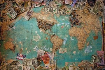 a map ofthe world with pins and currency of the world