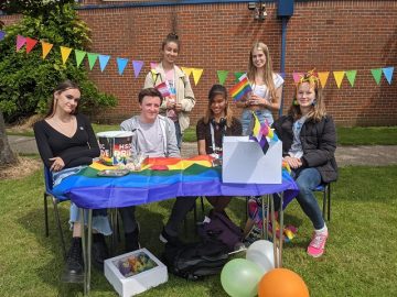 Students gather in front of rainbow bunting