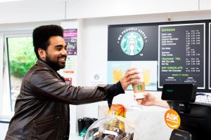 a student being handed a starbucks coffee by starbucks staff