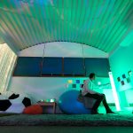 a person in the sensory room playing with the lighting, sat on a bean bag