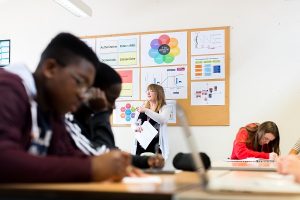 male students in with teacher in background